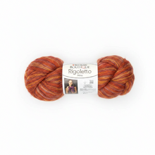 A skein of Rougeto yarn in a variegated rust, orange, and yellow colorway, wrapped with a white paper label, on a solid white background.